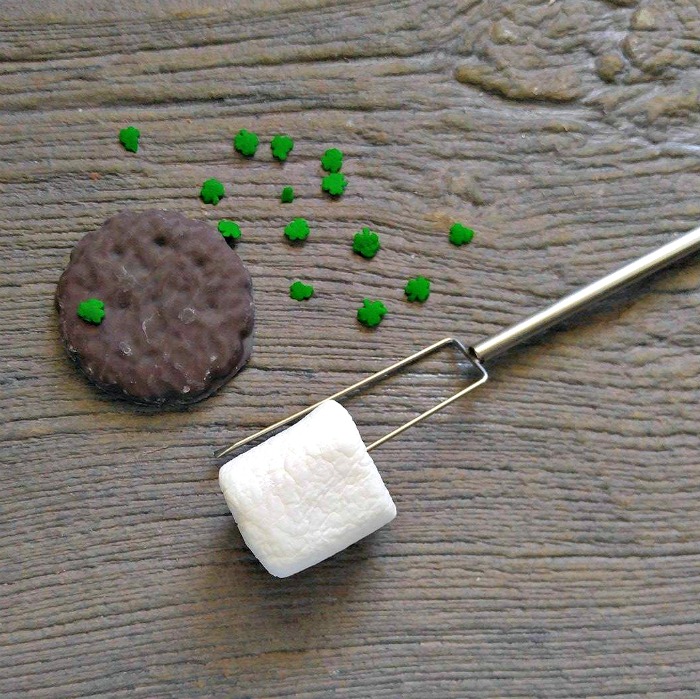 Girl scout cookie with shamrock sprinkles and a marshmallow on a metal fork.