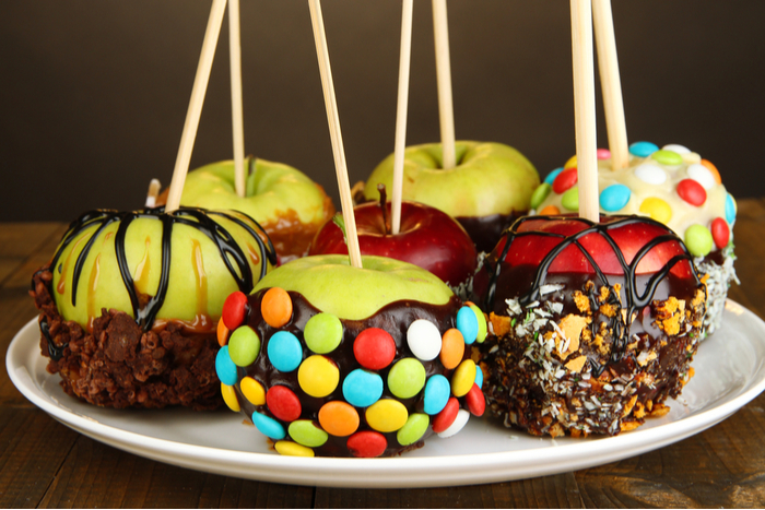 Caramel apples with candy toppings including M&Ms, sprinkles, and chocolate drizzle.