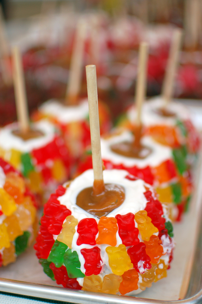 A plate of caramel apples with marshmallows and gummy bears.