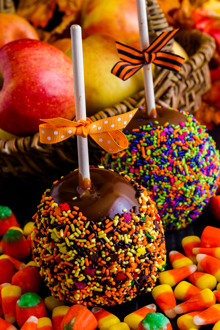 Two caramel apples for halloween with sprinkles.