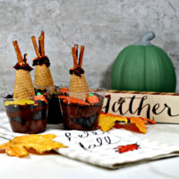 Dirt recipe chocolate pudding shaped like teepees, with sign towel, leaves and pumpkin.