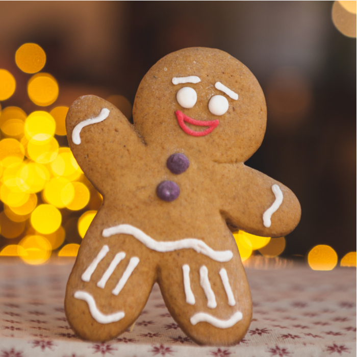 A gingerbread man cookie standing and waving.