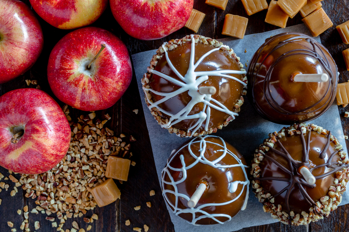 Two white chocolate caramel apples and two dark chocolate caramel apples on a plate. 