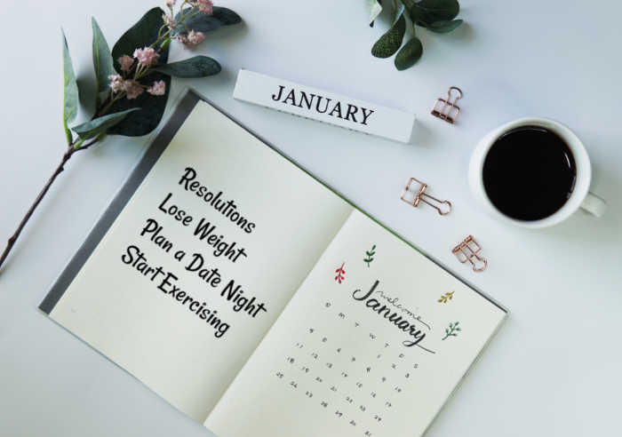 Calendar, flowers and coffee cup with a January journal with new years resolutions.