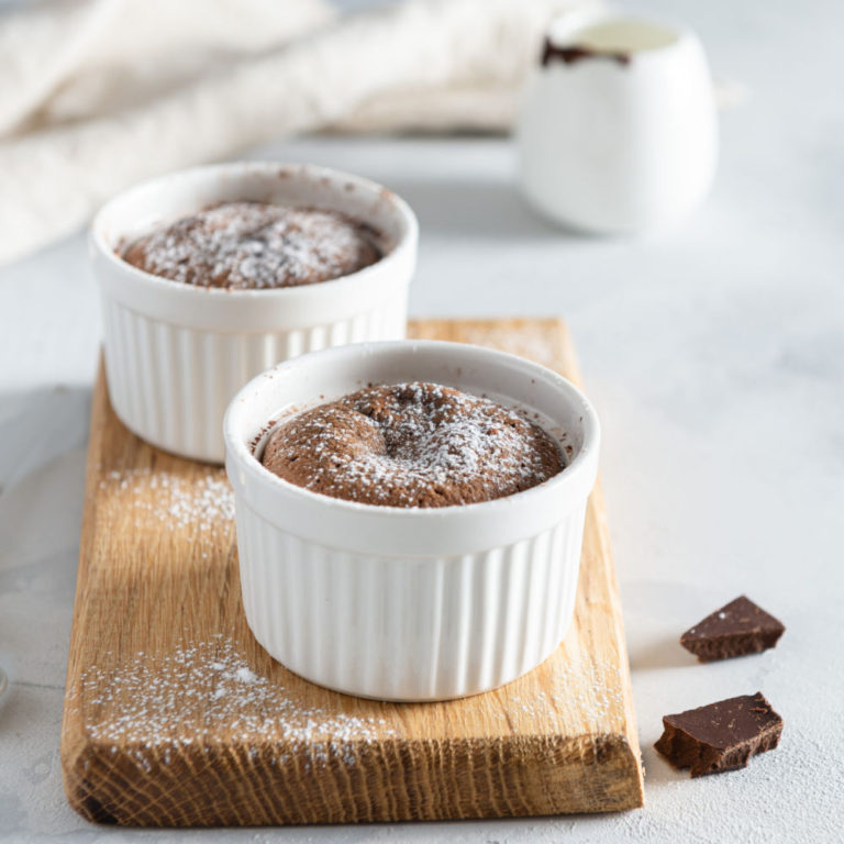 Chocolate soufflés on a cutting board with squares of chocolate for National Chocolate soufflé day.
