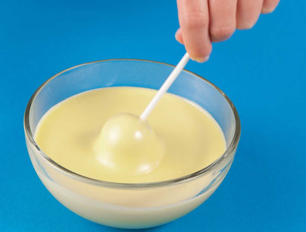 Dipping cake balls into melted white chocolate.