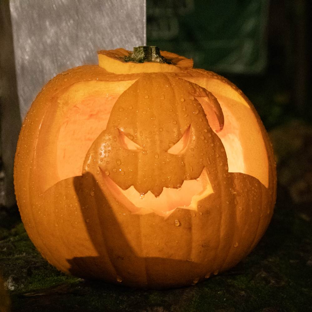 An Oogie Boogie pumpkin carving illuminated by a porch light.