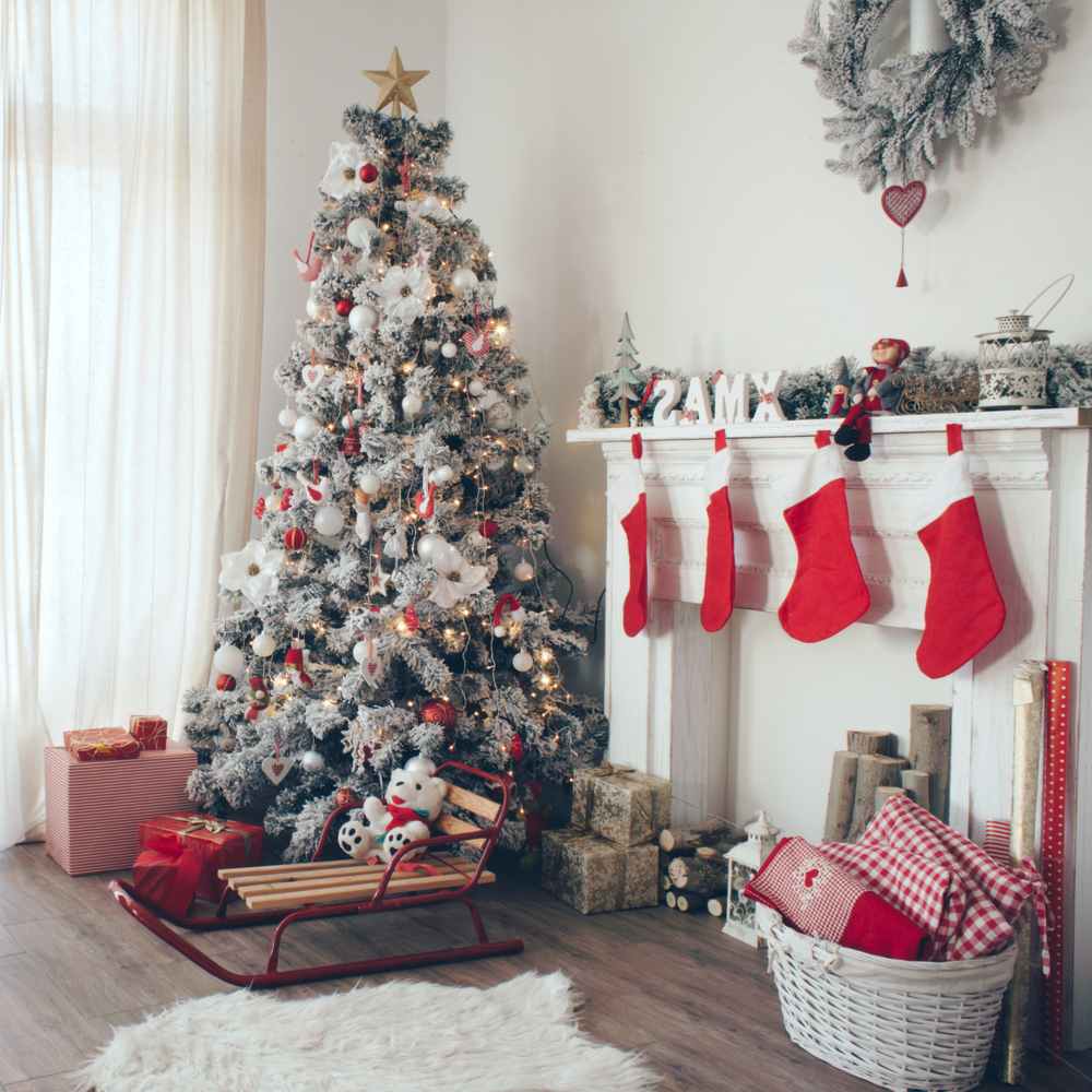 A beautifully decorated living room at Christmas time with a Christmas tree, four stockings hung on the mantle, a sled and a wreath on the wall.