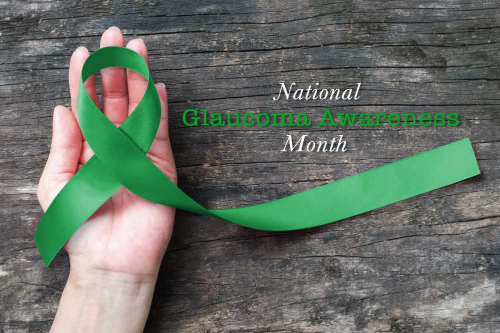 Hand holding a green ribbon with words national glaucoma awareness month.