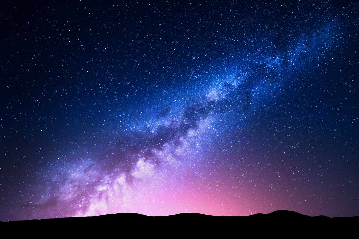 An image of the milky way against the night sky, which is dark blue at the top and pink at the bottom.