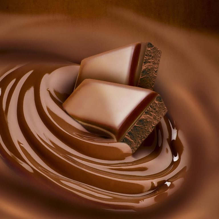 Two squares of milk chocolate floating in a swirl of melted milk chocolate.