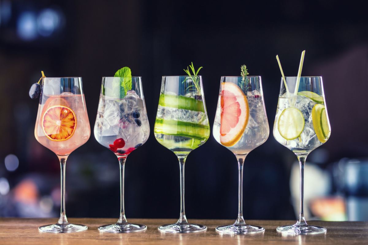 Five different fancy cocktails with fruit garnished to celebrate the national drink days of the year like National Mojito Day.
