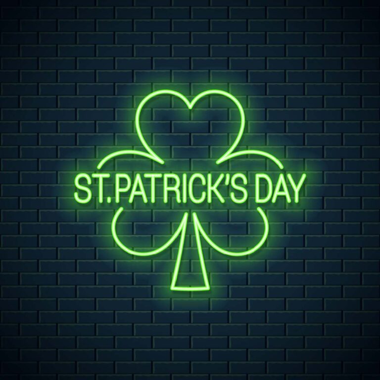 A black brick wall with a neon shamrock sign that says St. Patricks Day in the center of it.
